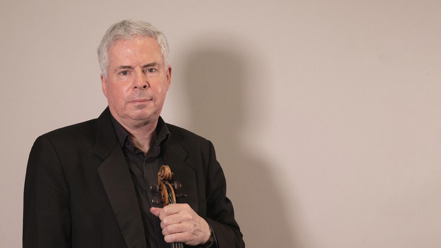 Sinfonia leader, Geoffrey Allan posing with his violin.