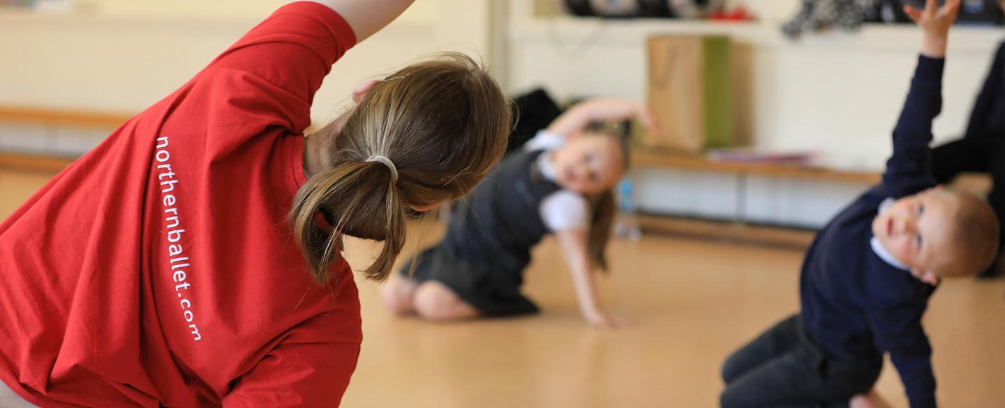 Teacher leads a class in reaching over their heads