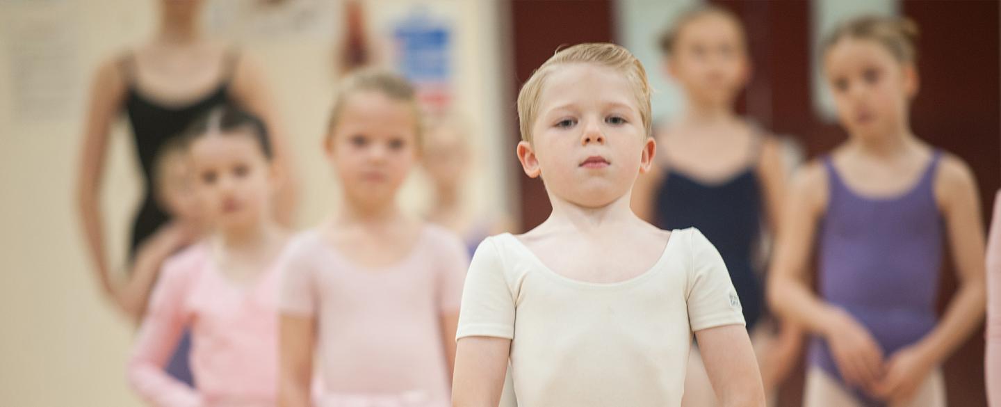 A boy stood with arms held in ballet position