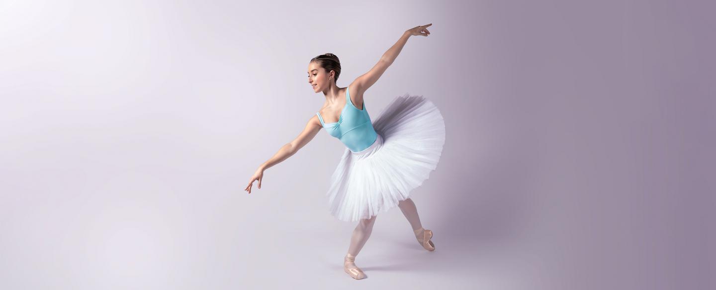 Female dancer in a blue leotard and white tutu on pointe