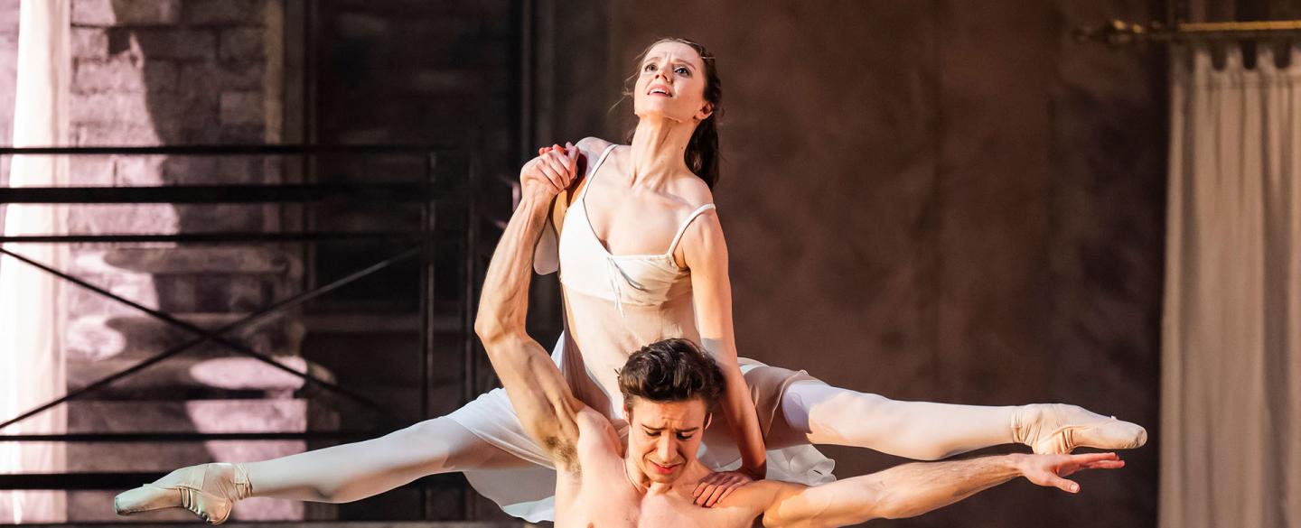 A female dancer in splits on the shoulders of a male dancer