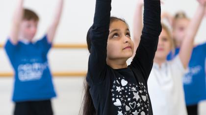 A class of children raise their hands in the air