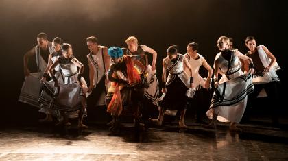 A group of dancers in costume holding the skirts of their dresses