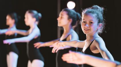 A little girl in a ballet show turning towards the camera smiling